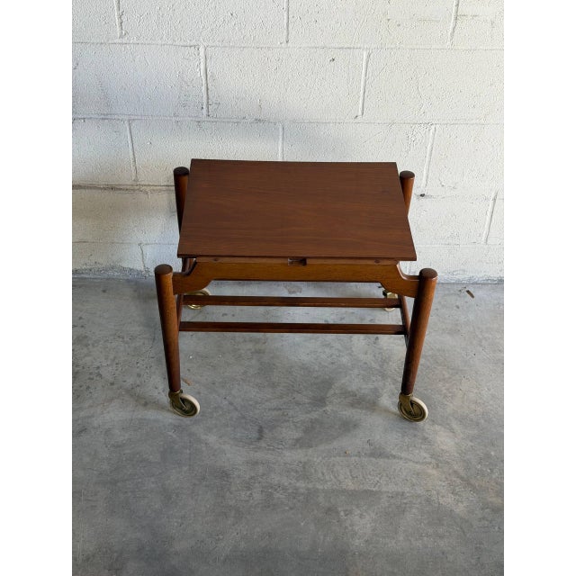 Vintage Danish modern teak bar cart featuring elegant Scandinavian craftsmanship, clean lines, and brass casters. The...