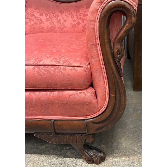 A striking American Empire Revival sofa featuring gracefully carved swan-form arms and a gently curved camelback...