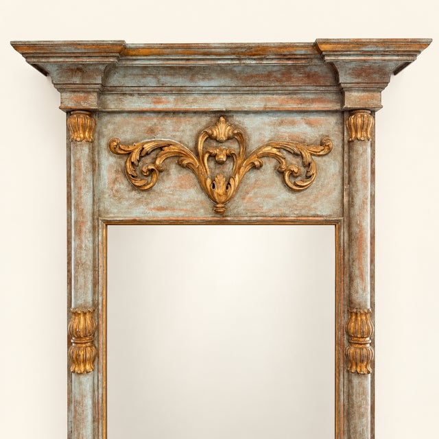 A grand neoclassical style pier mirror standing nearly seven feet tall. The frame is painted in a soft, timeworn blue-...
