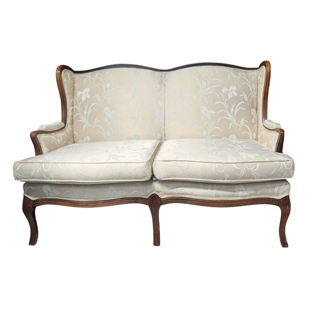 An elegant upholstered camelback loveseat by Southern Furniture Co. of Conover, North Carolina, Featuring a gracefully...