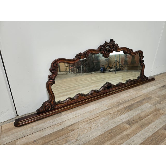 An elegant period Italian mirror, featuring a richly carved and shaped wooden frame with refined ornamental motifs of...