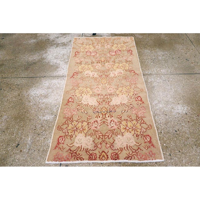 This mid-20th century Turkish Anatolian rug, measuring 2' 8" x 5' 4", showcases a soft, romantic palette and a graceful...