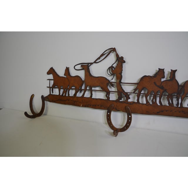 Metal horse and cowboy with three horseshoes, huck coat rack.