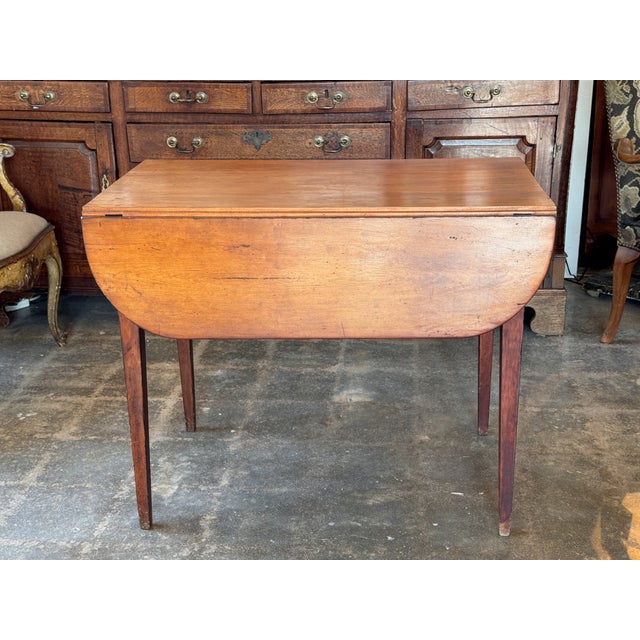 A 19th century Pembroke table with two drop leaves with rounded corners, a single dovetailed drawer with a brass swing...