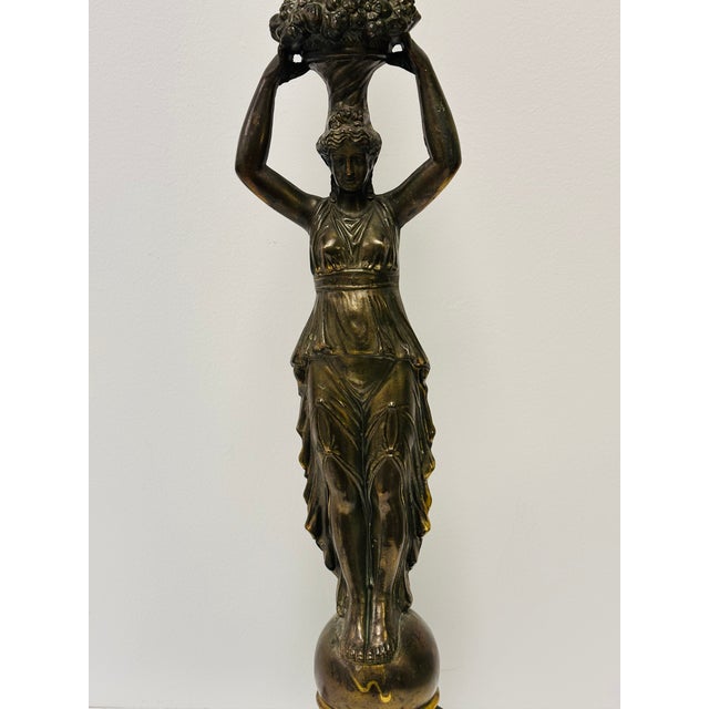 Elegant neoclassical Greco-Roman style sculpture of a classical female figure standing on a globe and holding up a basket...