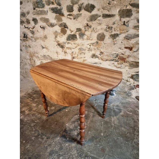 This French antique round drop-leaf table dates from the early 20th century and is crafted in solid walnut. The table...