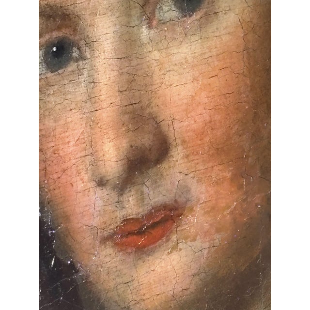 Oil on panel depicting the portrait of an elegant lady, bust-length, wearing a low-cut blue dress and adorned with a...