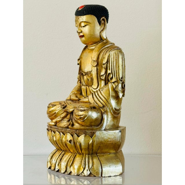 A carved and gilded figure of Buddha. Seated on a double lotus base with downward gaze. Chinese from the late 19th century.