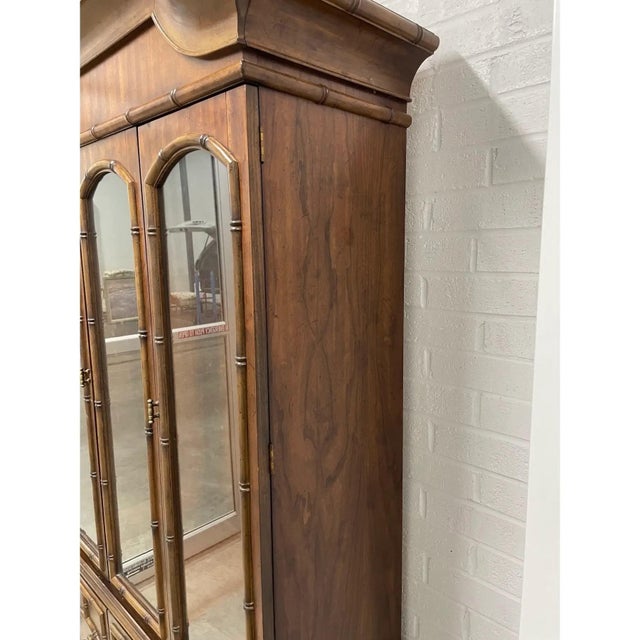 Offered is a two piece display cabinet featuring a pagoda style top, two adjustable glass shelves and hidden storage in...