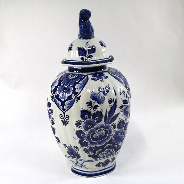 This Delft lidded vase, or ginger jar urn, boasts a classic blue and white floral design that highlights traditional Dutch...