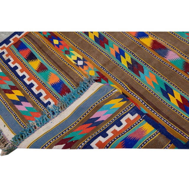 Beautiful kilim handmade wool runner with a brown field. This Vintage flatweave rug has multicolor accents features a...