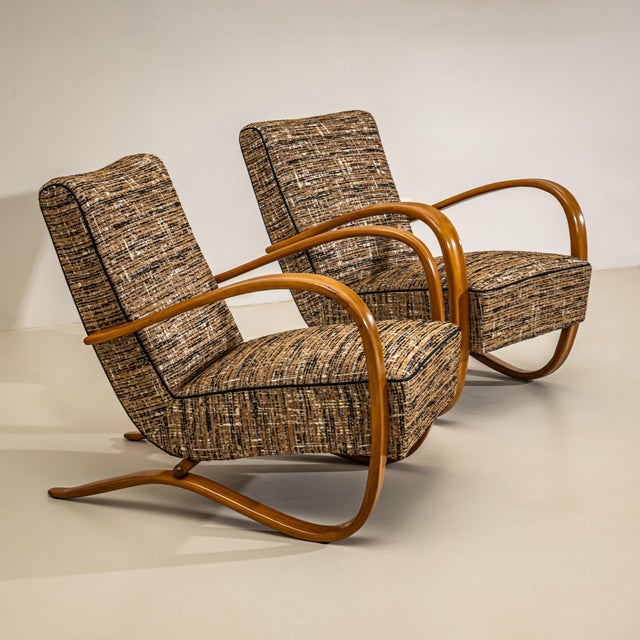 A pair of H-269 lounge chairs designed by Czech designer Jindřich Halabala in the 1930s. The distinctive, medium-brown...
