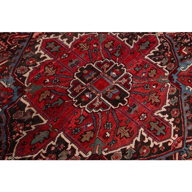 This is a stunning vintage Persian Heriz rug, artfully handcrafted using wool and featuring a vibrant red color field. The...
