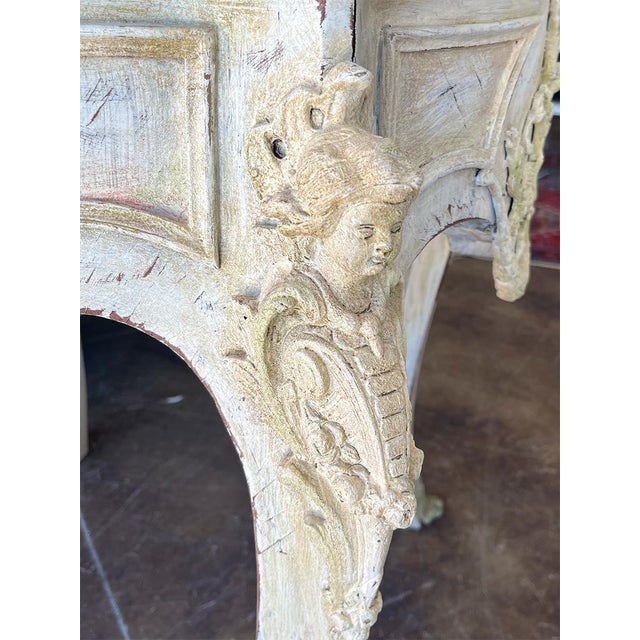 Carved figures on the corners, and cabriole legs. The base is cream, and the marble is white with gray veining.