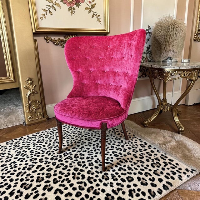 A dramatic vintage magenta velvet slipper chair with a wingback silhouette, low seat height, and sculptural profile suited...