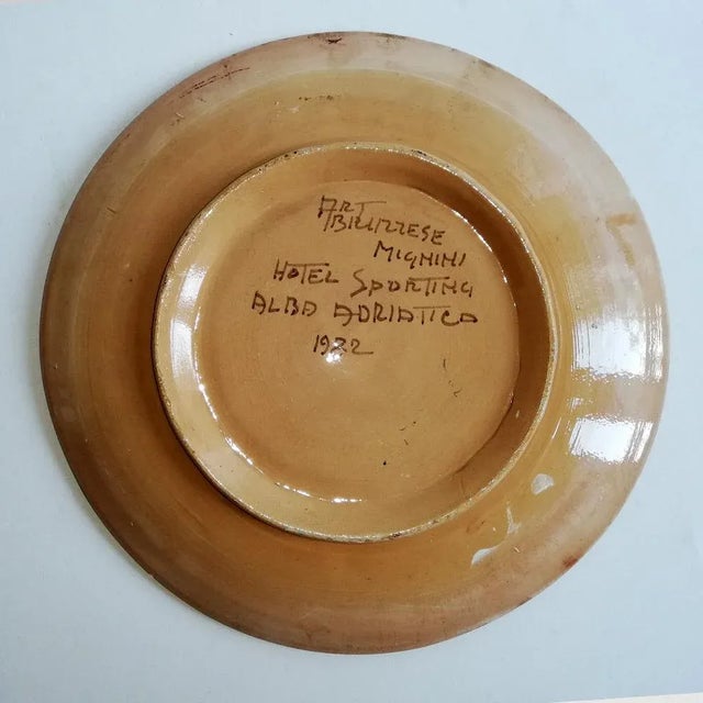 This floral plate comes in polychrome enamels. It is signed ART Abruzzese Mignini, Hotel Sportin Alba Adriatica, and is...