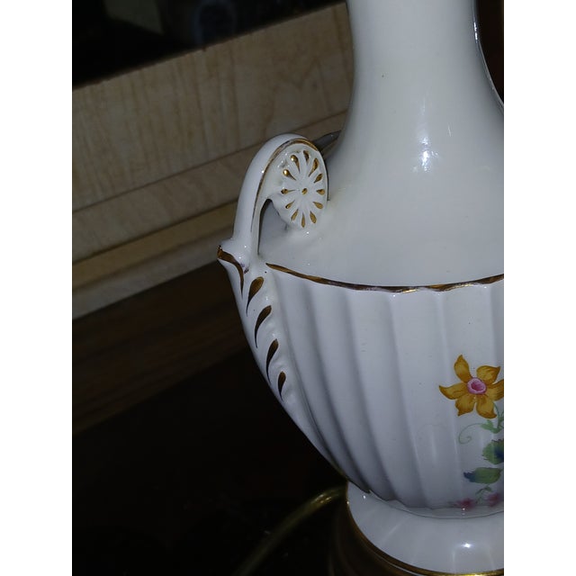 White base with painted floral bouquets and gilt gold accents. Features a gold-toned or gilt base, consistent with antique...