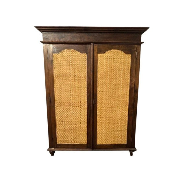 Vintage Indonesian armoire featuring beautifully handwoven natural rattan door panels set in a solid wood frame. Warm,...