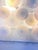 Nine mouth-blown glass discs, each featuring a satin-white opaline core encircled by a ring of clear crystal, form the...