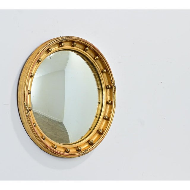 An English Regency style convex mirror from the 19th century that would be right at home in the interior design tastes of...