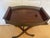 Listed is a vintage wooden folding serving tray table featuring a rich, dark wood finish, decorative metal gallery sides,...
