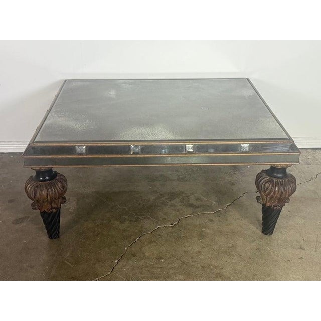 A striking Hollywood Regency–style coffee table featuring a fully mirrored top and apron, elevated on dramatic carved wood...
