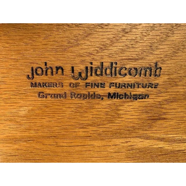 A John Widdicomb mid-century period credenza in walnut. Carved and gilded in front, three central drawers and cabinets at...