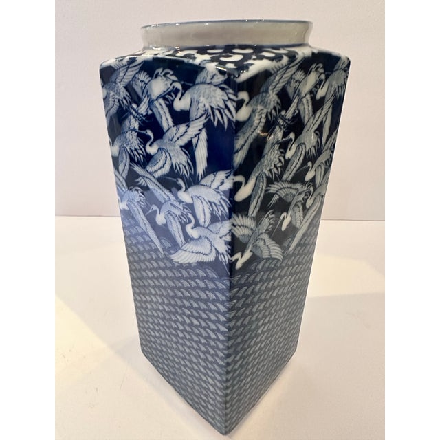 This elegant Japanese porcelain vase features a striking indigo‑blue and white design of soaring cranes above a stylized...