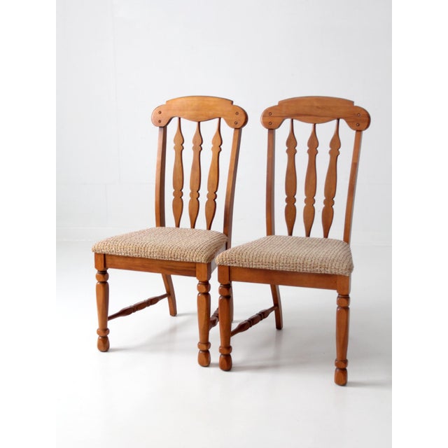 Pair of vintage mid-century wood dining chairs with tall shaped backs, carved splats, and turned front legs. Warm wood...