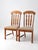 Pair of vintage mid-century wood dining chairs with tall shaped backs, carved splats, and turned front legs. Warm wood...