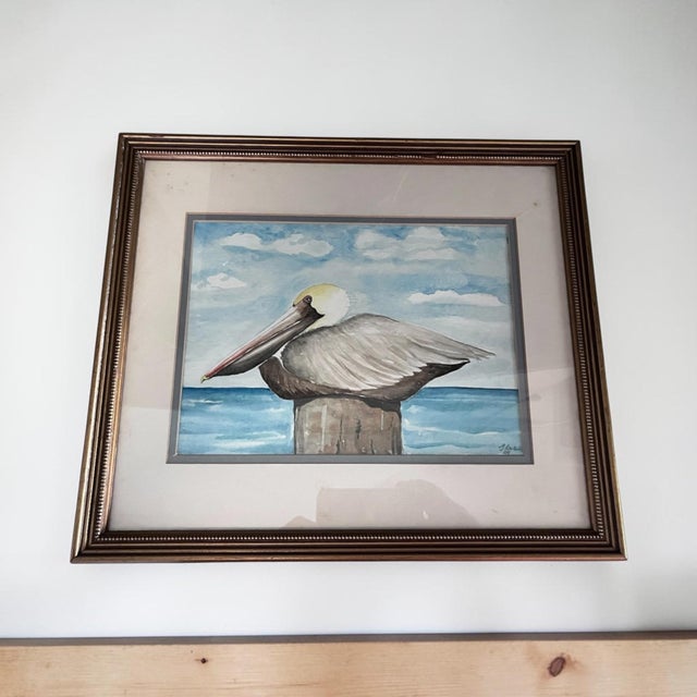 Bring coastal charm to any interior with this original watercolor, “Pelican Resting,” by artist Ilse Wolff, signed and...
