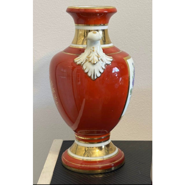 This exquisite vintage Noritake vase showcases a bold red porcelain body with intricately hand-painted floral panels and...