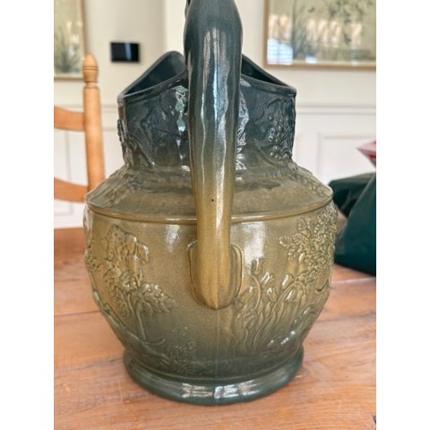 A richly sculpted late 19th-century majolica pitcher featuring a beautifully modeled hound-form handle and high-relief...