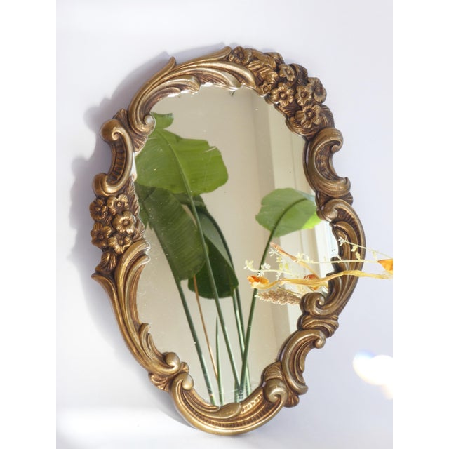 A vintage French golden wall mirror with an ornate frame. The mirror is made out of plaster and is branded in the back...