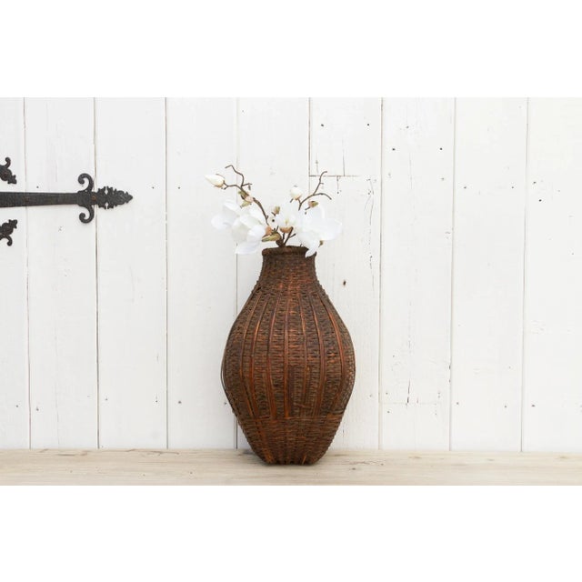 Originally used to trap and transport fish. This antique woven basket from Nepal has a bottle shape with a rounded body...