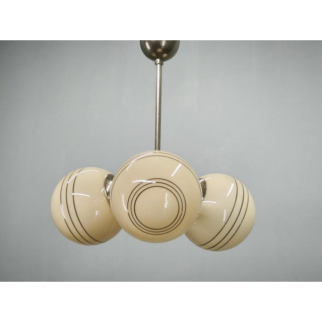 Elegant Art Deco chandelier manufactured in Czechoslovakia during the 1930s, featuring a sophisticated composition of...
