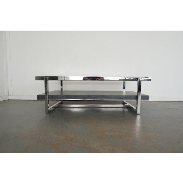 A sleek vintage coffee table from the late 1970s to 1980s, featuring the crisp lines and chrome-and-glass look that...