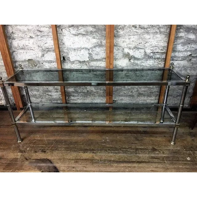 Well constructed polished chrome and brass console with polished brass ball finials and brass Greek key accents. Designed...