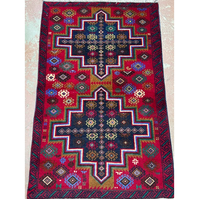 Afghan Balouch rug, hand knotted in Afghanistan from 100% wool. Measuring 2’8” x 4’4”, this vibrant tribal rug features...