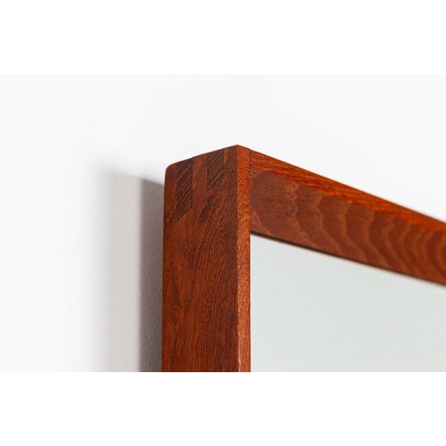 A beautiful and elegant rectangular wall mirror made in Denmark during the 1960s. The mirror features a slender solid teak...