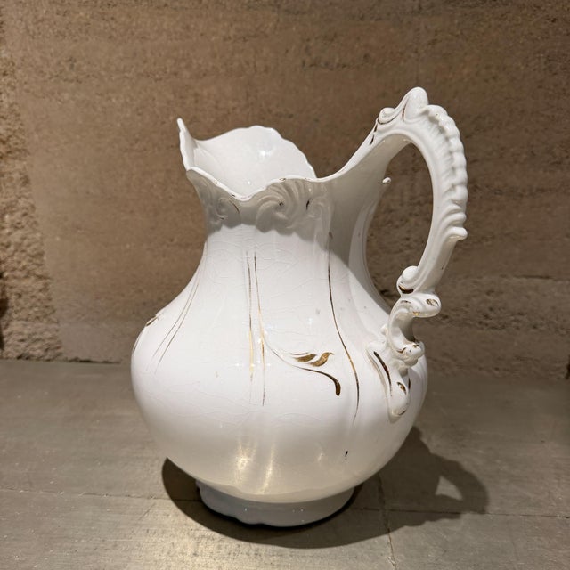 For your consideration, antique white porcelain pitcher features delicate gold trim accents and a ornate scalloped handle....