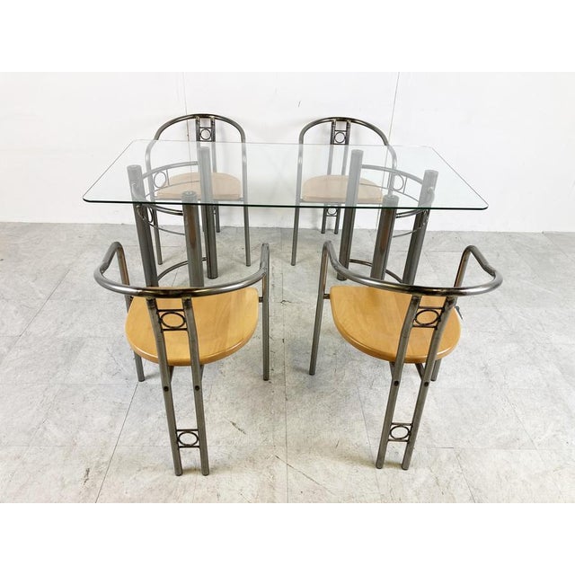 Vintage custom made dining chairs with armrests and dining table with a clear glass top. The chairs have a wooden seat....