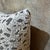 The cover carries a scattered leopard spot pattern across a white chenille ground, the dark charcoal spots distributed...