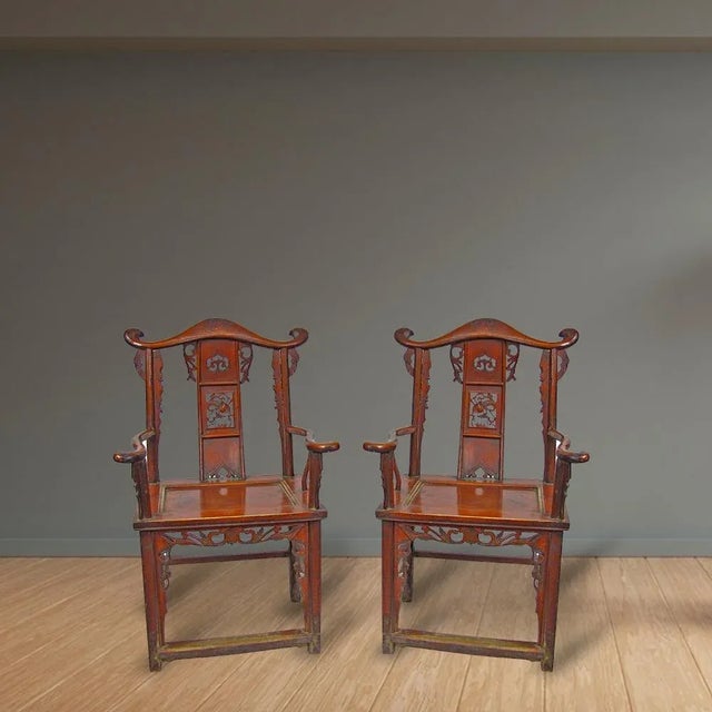 This pair of 20 century antique armchairs is adorn with elaborate carving on the back splat and around the chairs and...