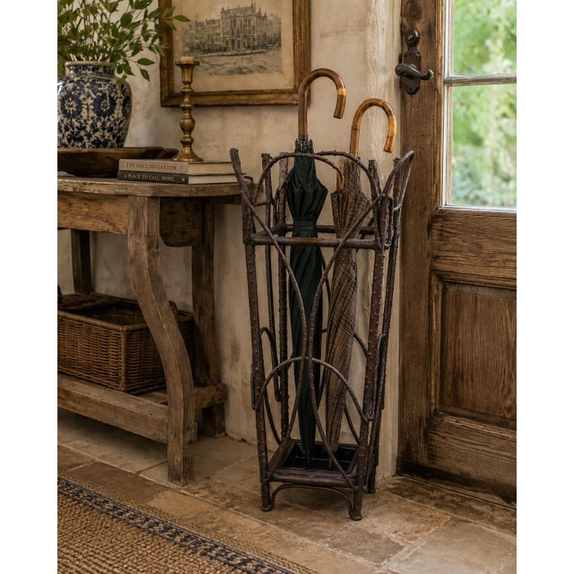 A beautifully crafted early 20th century iron umbrella stand featuring an exceptional trompe l'oeil faux twig design that...