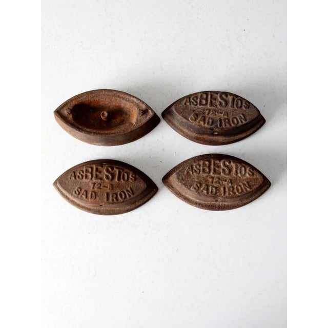 This is a collection of four antique sad irons dating to the late 19th century. The heavy flat iron bases include three...
