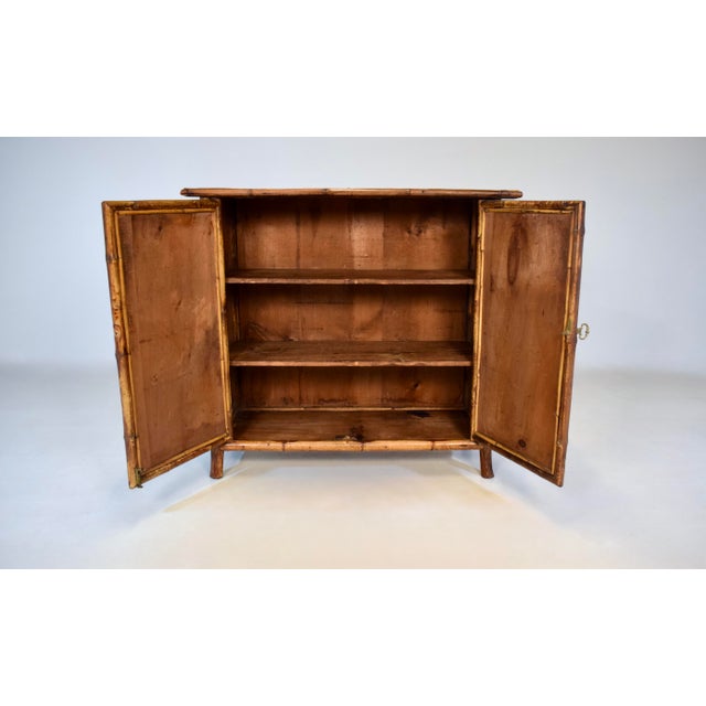 A late Victorian Tortoise Bamboo two door console cabinet with original painted textured grass cloth surround and two...