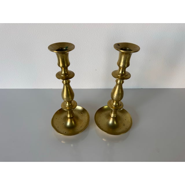 Classic pair of vintage solid brass candlestick holders featuring elegant, turned silhouettes with wide, sturdy bases....