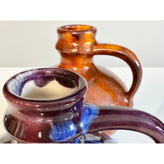 A pair of handcrafted stoneware vases with an unknown signature. The pair is striking for its vibrant glaze: one vase...