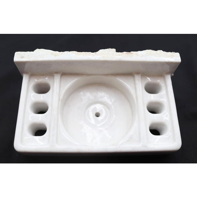 Flush mount bathroom cup and toothbrush holder made of white porcelain over ceramic. Good condition with surface wear and...